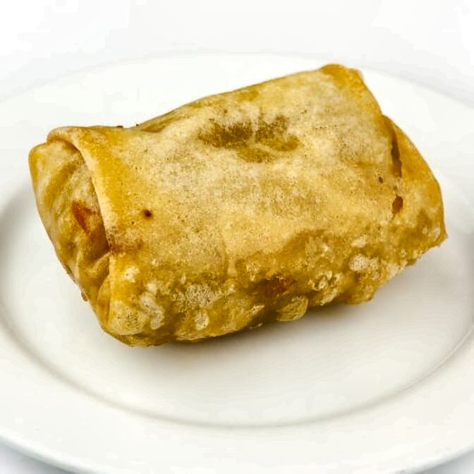 A single golden fried egg roll on a white plate.