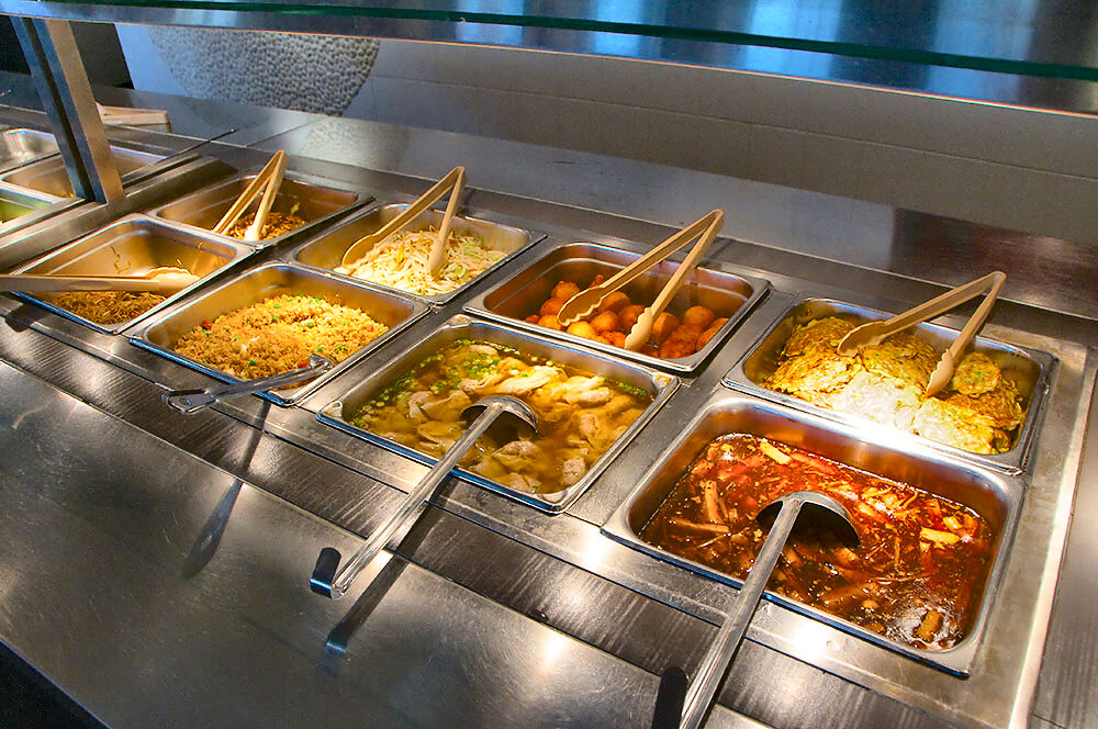 Close view of the buffet with chow mein, vegetable fried rice, bean sprouts, breaded sweet-and-sour balls, chicken and vegetables in broth, and egg foo young.